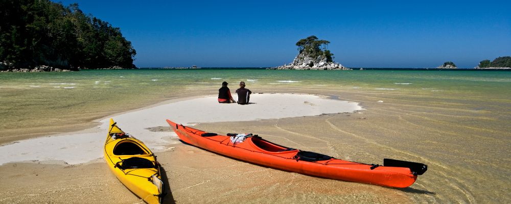 Two people on the beach with their kayaks